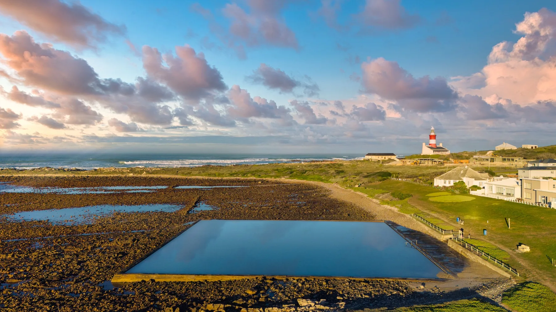 Broad Cape Agulhas coastline, sea and lighthouse under a summer sky with soft clouds