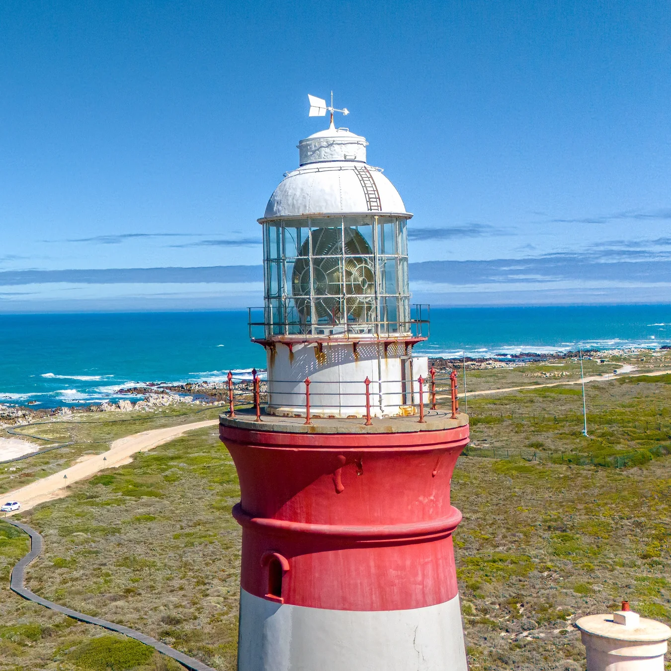 Cape Agulhas lighthouse rising above the rocky southern coastline beneath a clear blue sky