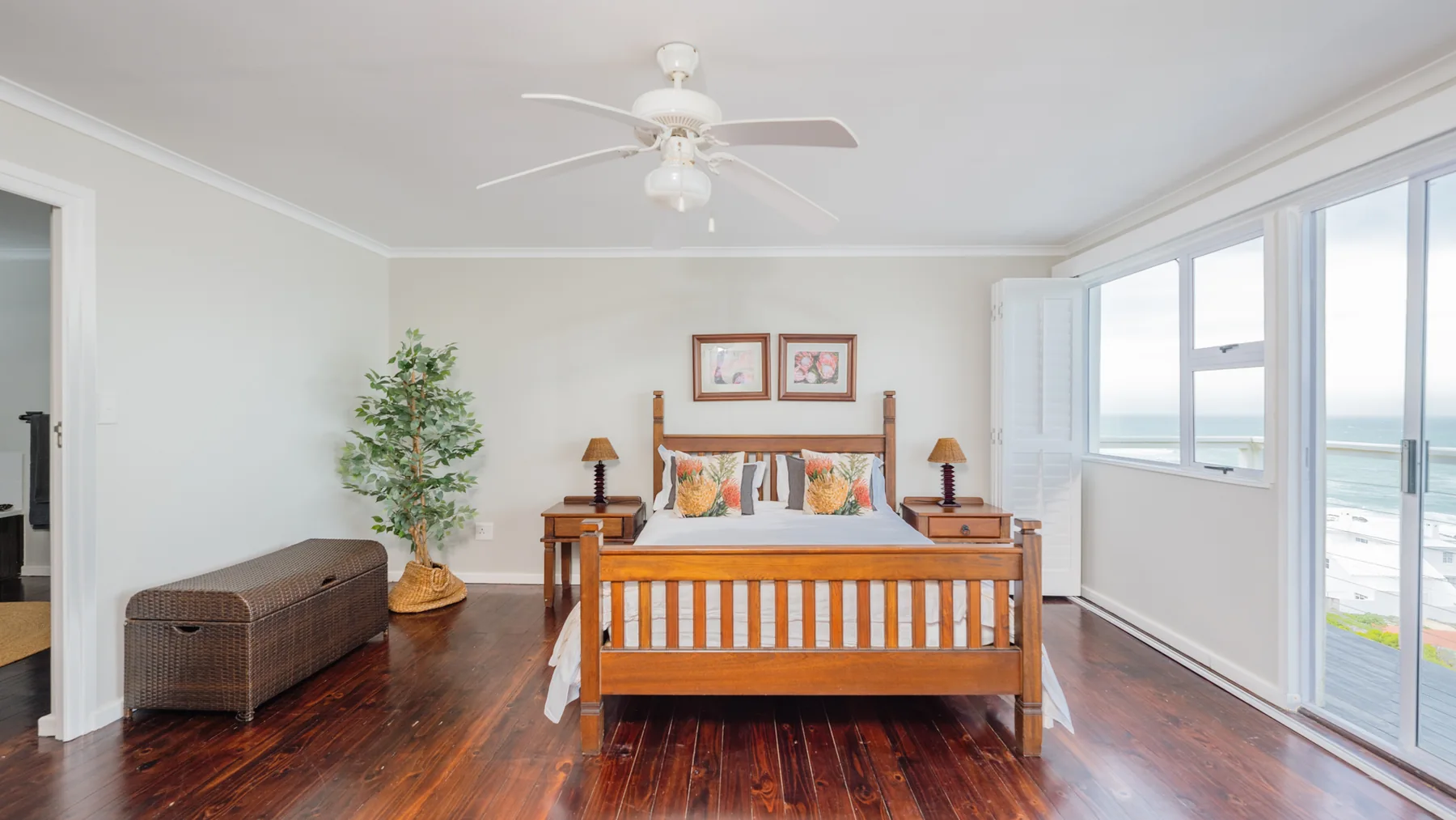 A bright timber-framed bedroom with a window overlooking the sea